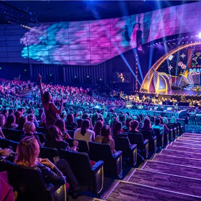 A packed theater audience watches BravoCon Live under purple stage lights