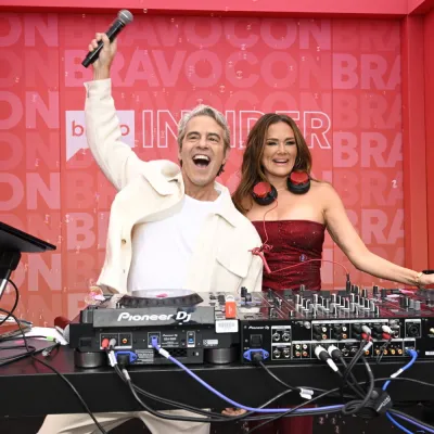 Two hosts celebrate behind the DJ decks on the Bravo Insider stage