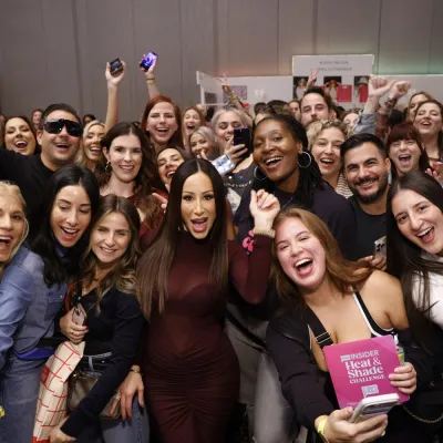 A cheering crowd of fans gathers around a Bravo star for a group photo