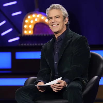 A host smiles from an armchair on a neon-lit BravoCon stage