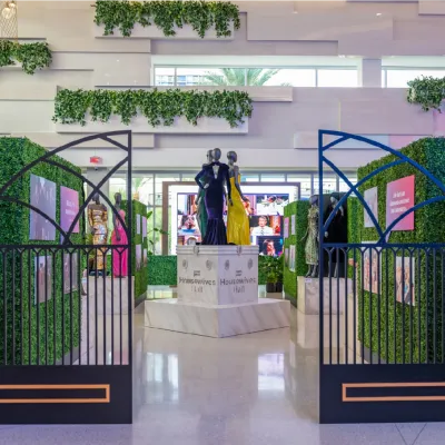 The entrance to Housewives Hall, framed by hedge walls and wrought-iron gates